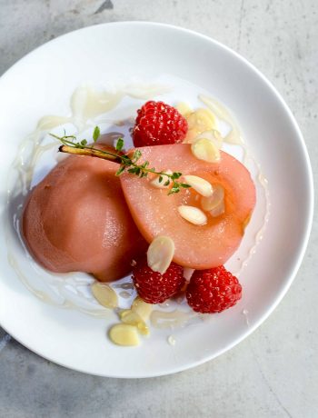 poached pears on a plate with raspberries
