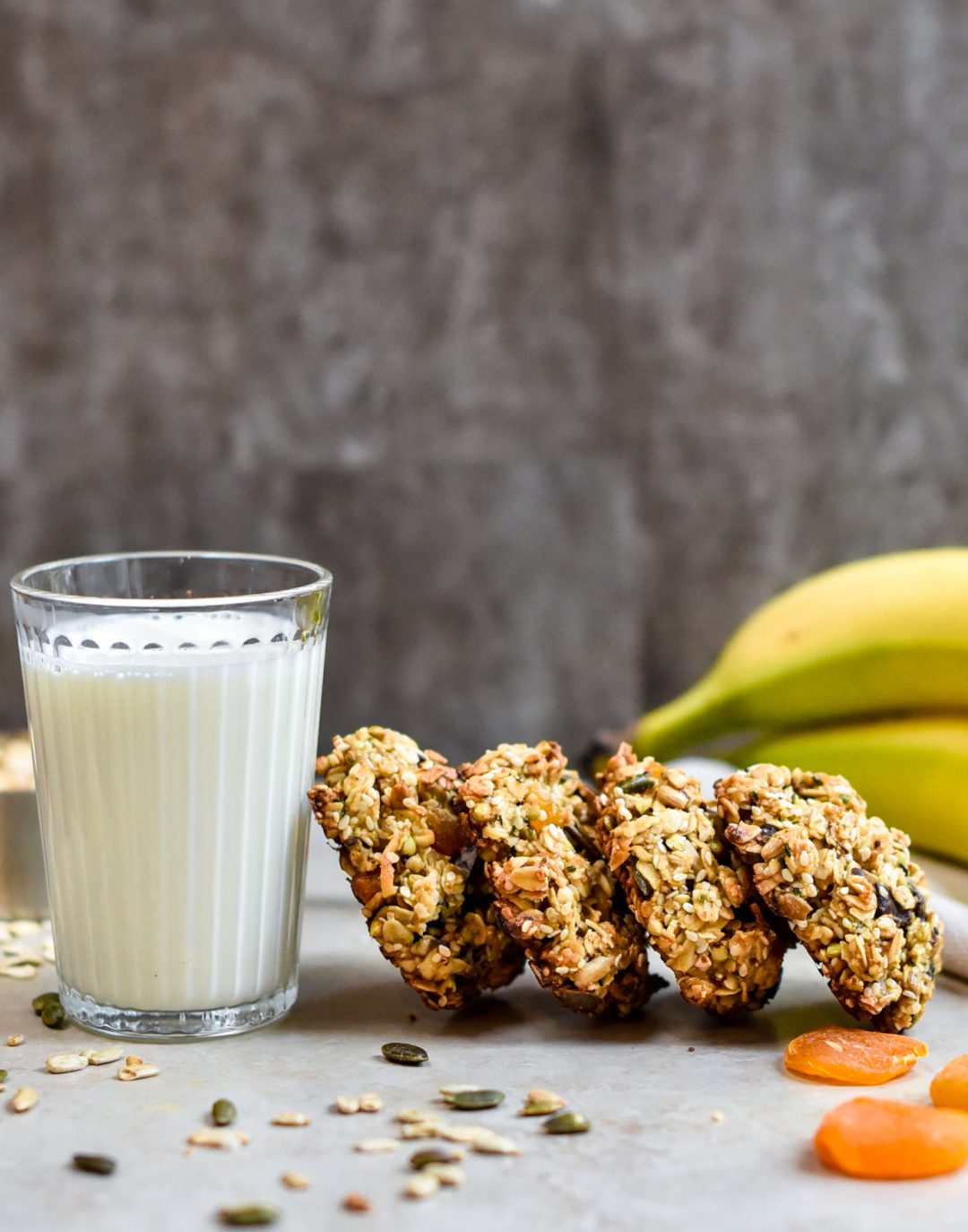 granola cookies leaning against glass of milk with bananas and seeds