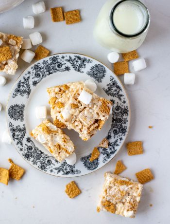 rice krispie squares on plate with cereal and marshmallows around it